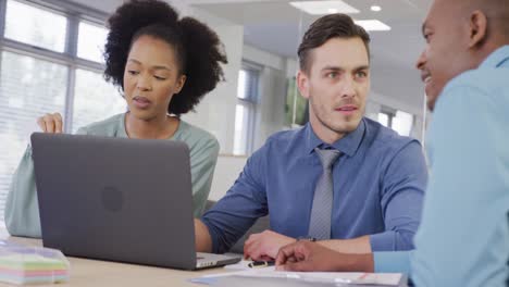 Happy-diverse-business-people-discussing-work-and-using-laptop-at-office,-slow-motion