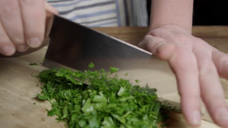 chef cortando perejil plano con un cuchillo en una tabla de cortar