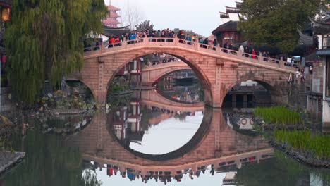 crowded stone bridge over canal in ancient chinese town
