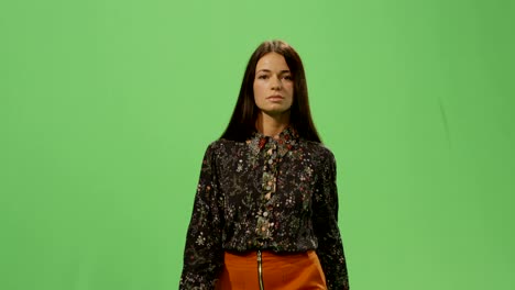 una mujer morena casual está caminando en una maqueta de pantalla verde en el fondo.