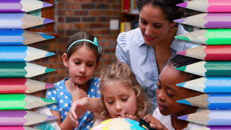 varios lápices coloridos contra una maestra y un grupo de niños que usan el globo en la escuela