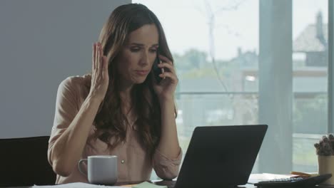 mujer de negocios hablando móvil. freelancer concentrado trabajando con documentos.
