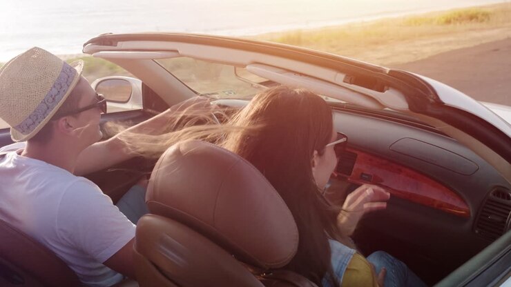 una pareja disfrutando de un viaje por carretera al atardecer en un descapotable