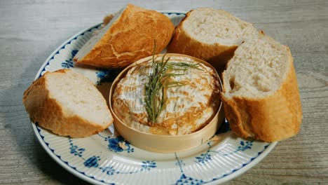 por el que se establece el queso camembert francés recién horneado con romero y trozos de pan baguette