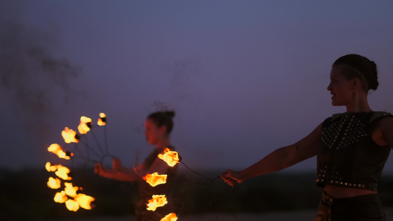 전문적인 서커스 공연자 그룹은 불을 던지고 불꽃을 던지는 물체를 회전시키는 것을 사용하여 느린 동작으로 댄스 쇼를 보여줍니다.
