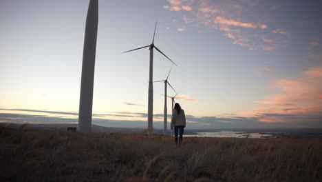 Model-walking-below-windmills-at-sunset-in-slow-motion