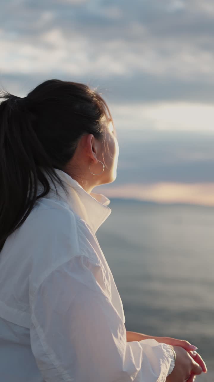 Giovane donna che guarda il mare al tramonto