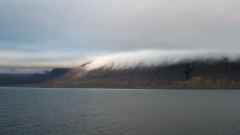 mountains under cloud cover from icelandic bay, long shot