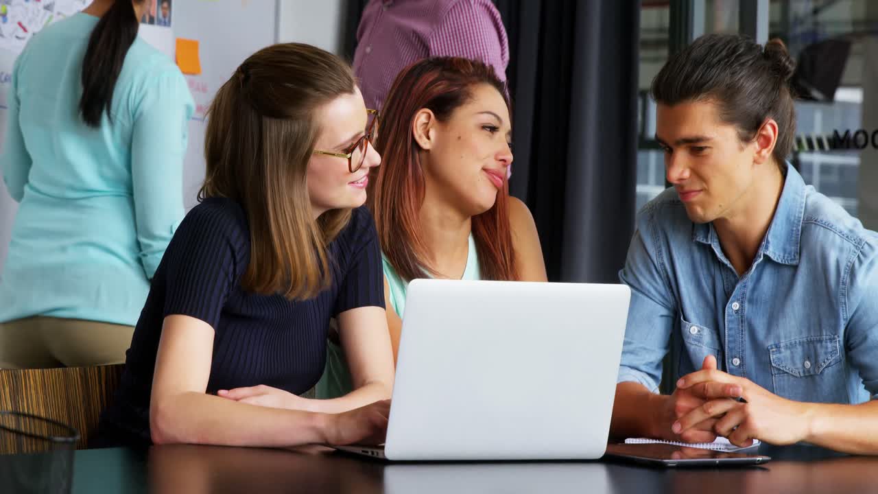 ejecutivos de negocios interactuando mientras discuten en la computadora portátil