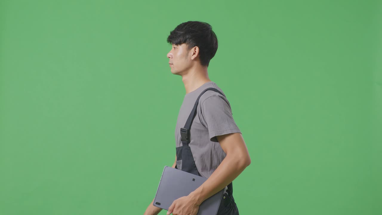 녹색 스크린에서 오버얼을 입은 태블릿을 들고 는 남자