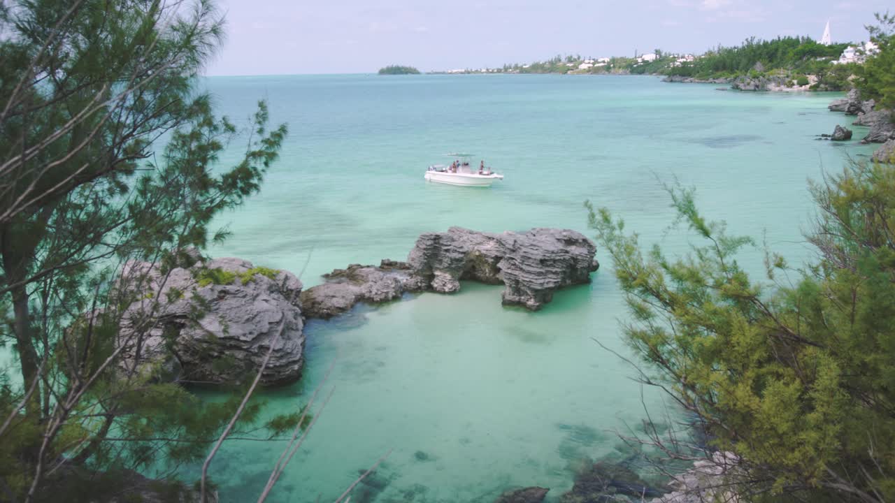 Bermuda near Morgan's Island, motor boat pulling into natural sheltered cove with shallow turquoise water and tropical coastline