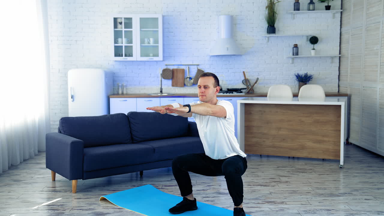 Sportman doing exercise at home. Man doing squats and exercising in living room at home