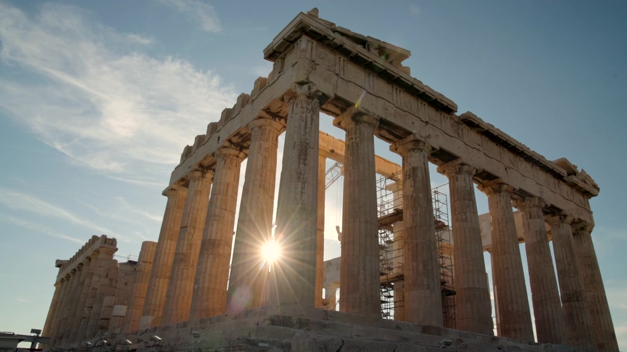 Luce del sole dell'ora d'oro che filtra attraverso antiche colonne di pietra all'Acropoli, evidenziando la bellezza senza tempo dell'architettura greca classica.