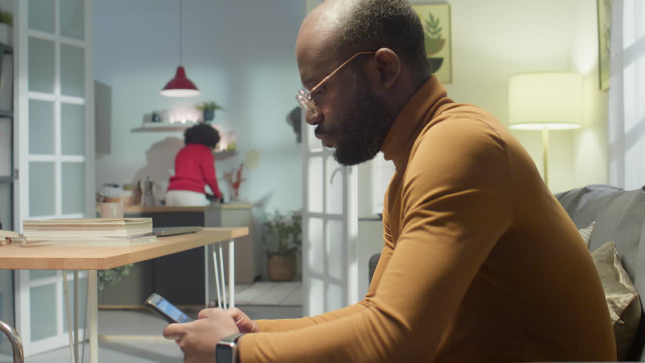 African American Man Texting on Phone at Home
