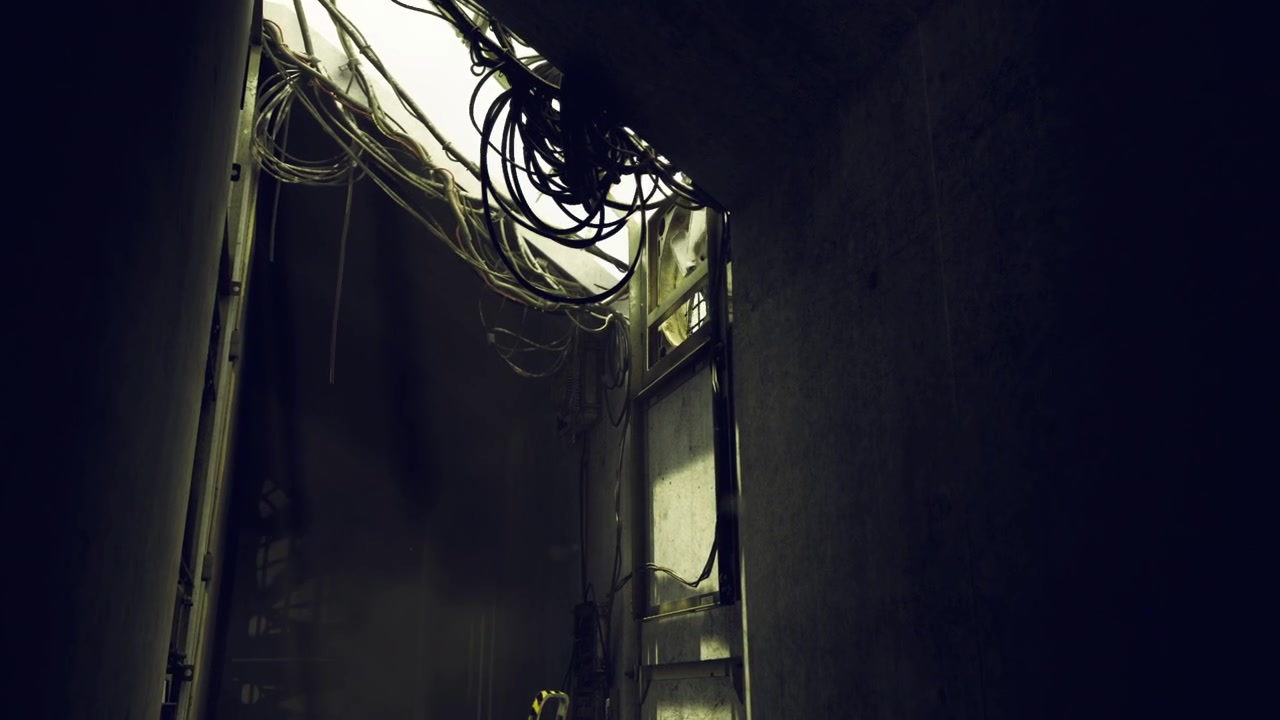 Estrutura subterrânea abandonada com cabos pendurados e luz sinistra.