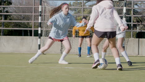 active teenaged girls playing soccer outdoors on sunny day