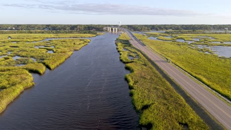 Plano aéreo acercándose al puente sobre el canal intracostero que lleva a Sunset Beach, Carolina del Norte