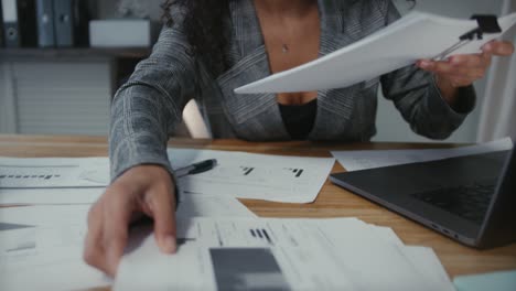 mujer latina trabajando con papeleo dentro de una oficina, empresaria latina sin rostro analizando los resultados de una empresa