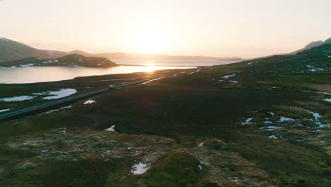 Vehicle-driving-lake-Kleifarvatn-long-curving-road-surrounded-by-lava-mountains-at-sunset,-Aerial-orbiting-view