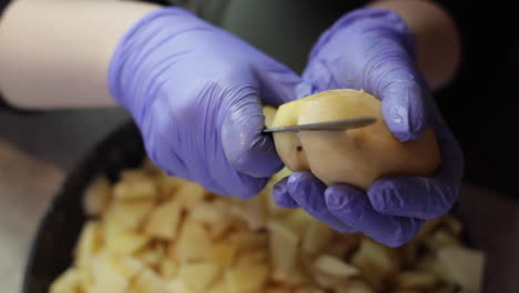 Close-Up-Retrato-De-Persona-Caucásica-Con-Guantes-Morados-Cortando-Patata