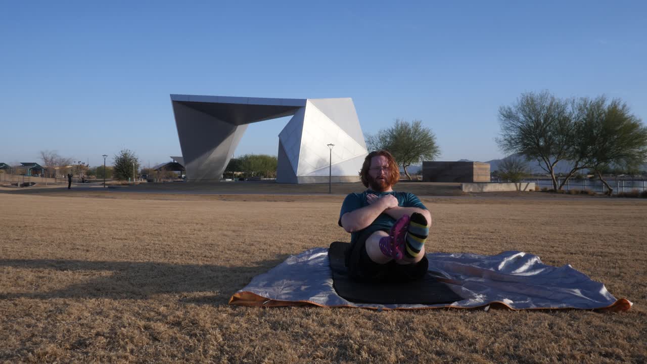 Red hair male doing leg raises in a Gilbert Arizona park amphitheater behind.