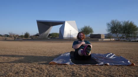 red hair male doing leg raises in a gilbert arizona park amphitheater behind.