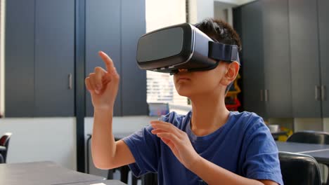 Vorderansicht-Eines-Asiatischen-Schuljungen,-Der-Am-Schreibtisch-Sitzt-Und-Virtual-Reality-Headset-Im-Klassenzimmer-4K-Verwendet