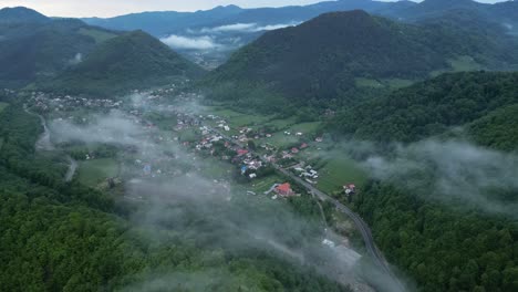 rural town down forested valleys during foggy sunrise in lepsa, vrancea county, romania