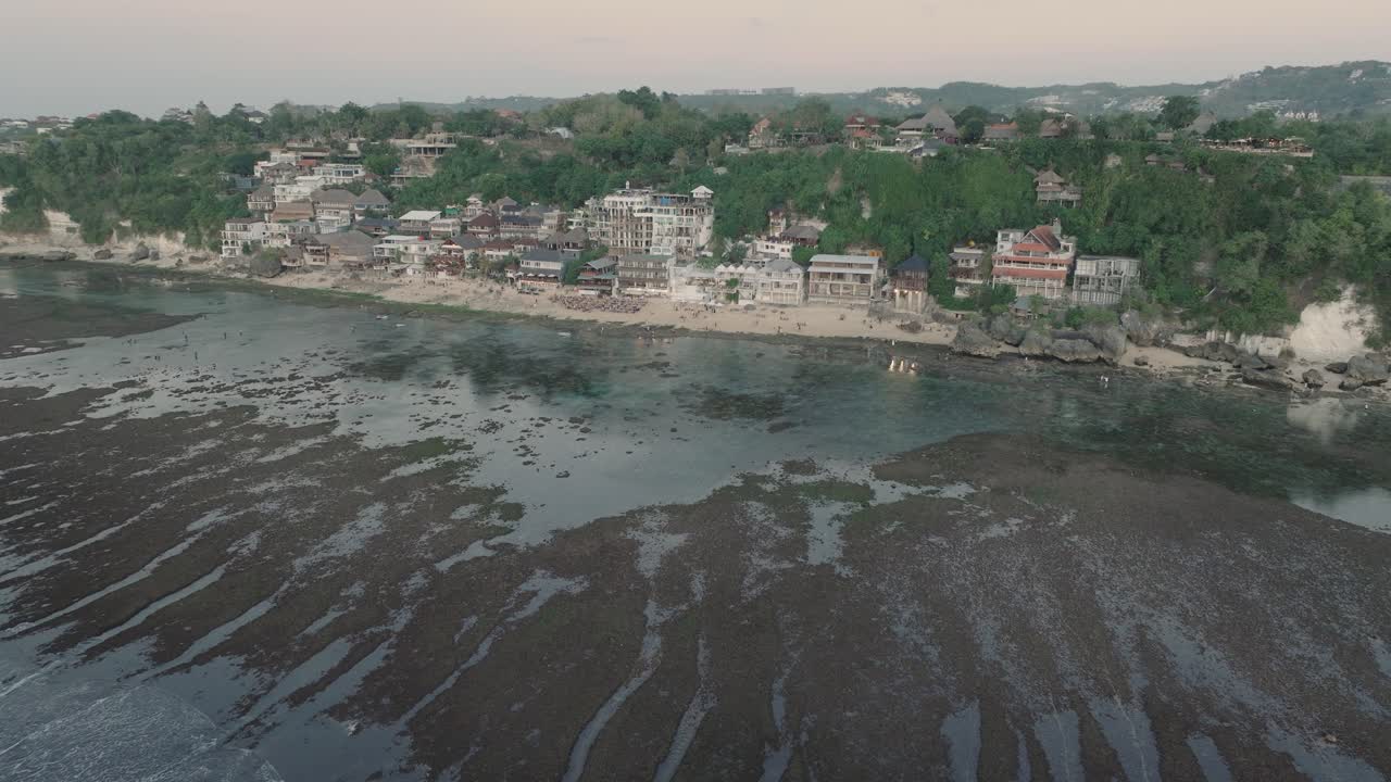 Medium Panning Drone shot of Bingin Beach buildings at sunset and low tide in Uluwatu Bali Indonesia