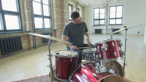 male drummer playing music in loft studio