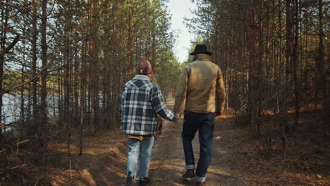 couple holding hands while walking with dog in forest