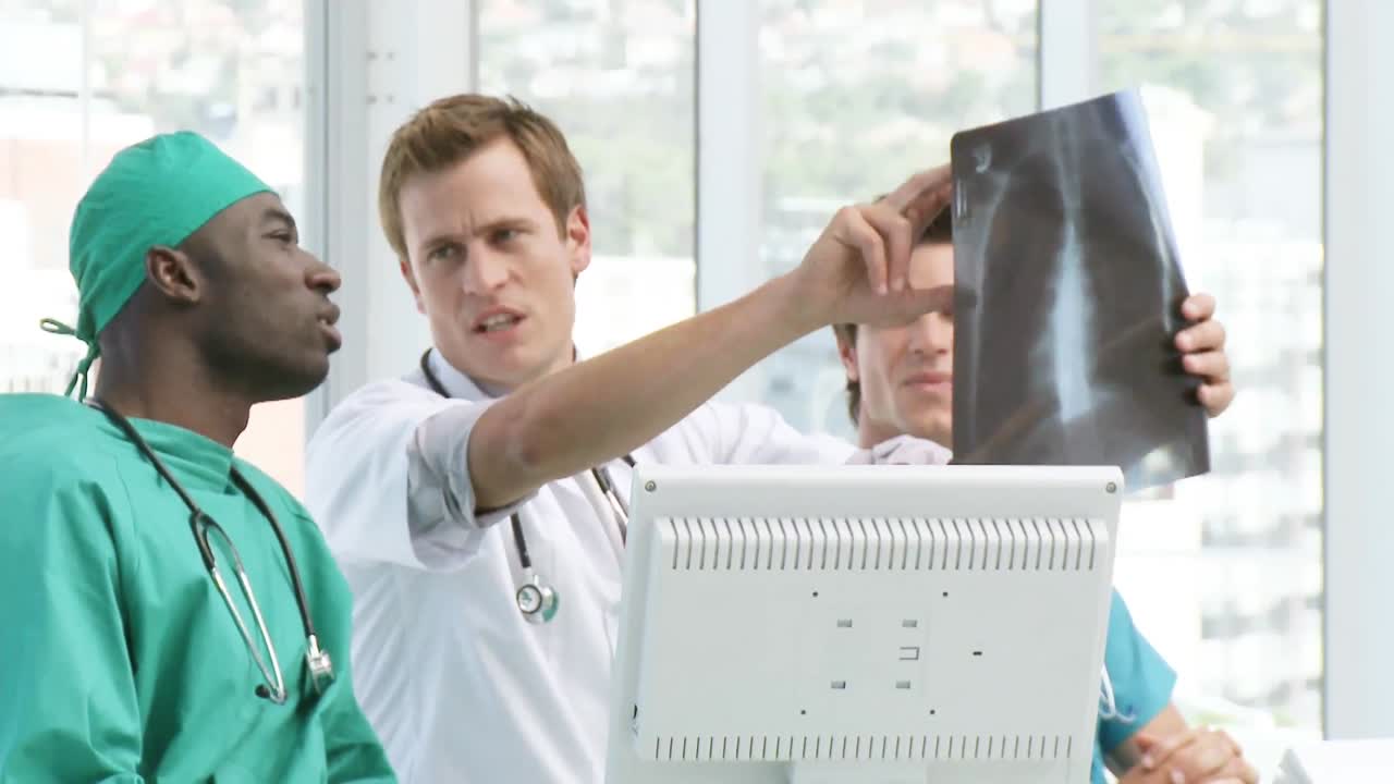 tres médicos discutiendo una tomografía computarizada