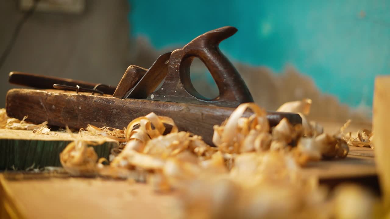 Wood planer lying in a carpenter workshop with wood waste, closeup of carpenting tools, process of making wood furniture, professional carpenting tools