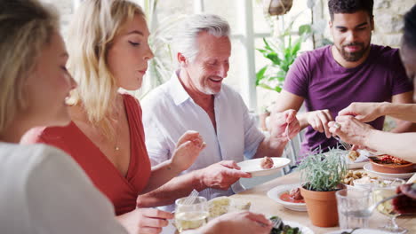 a mixed age group of adult friends eating tapas together at a table in a restaurant, selective focus