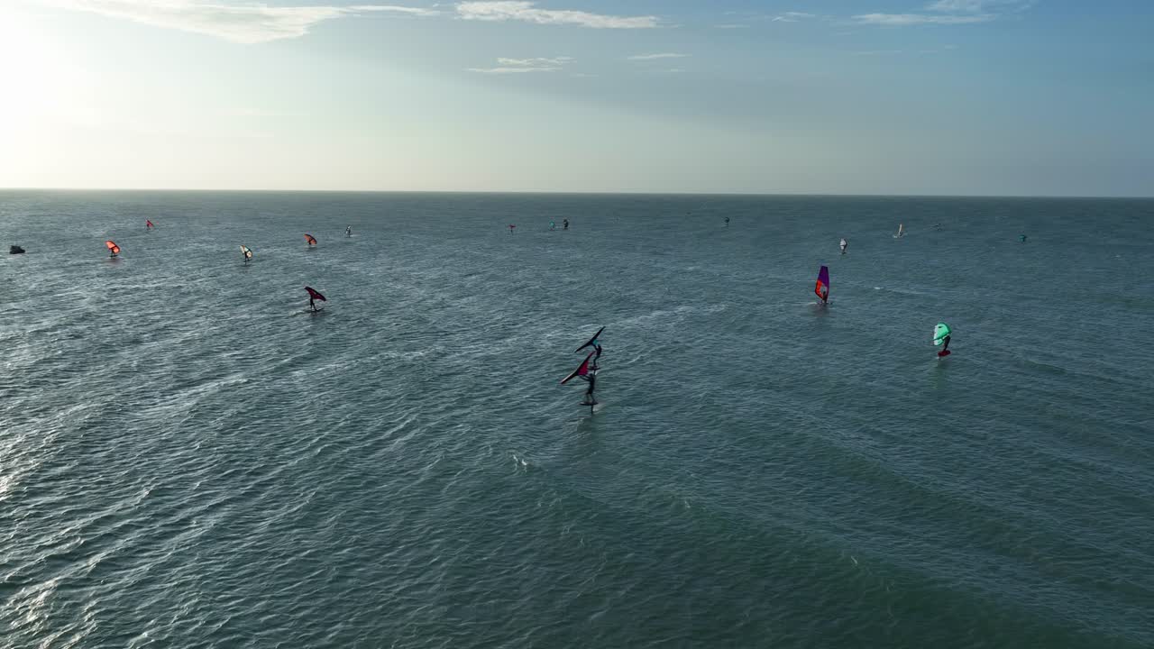 Shallow turquoise waters off Jericoacoara coast, Brazil, with wingfoiling wing boarding riders stretching out to distant horizon