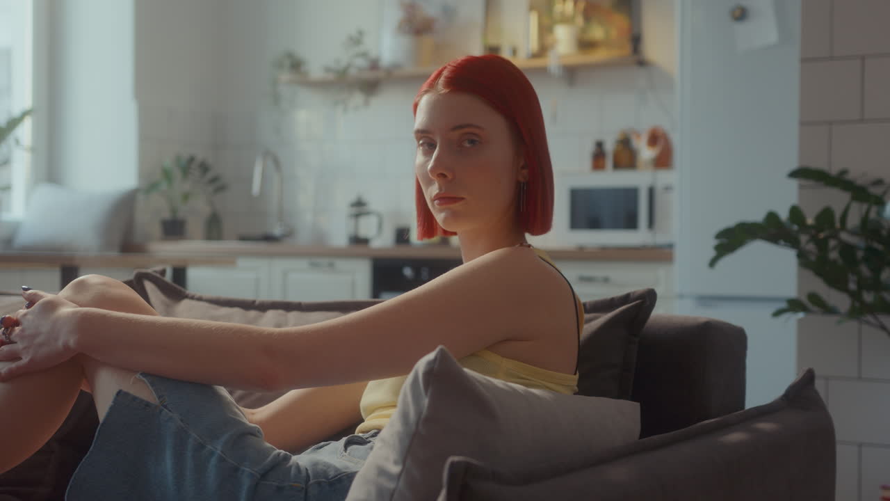 retrato de una hermosa chica pelirroja sentada en el sofá en la sala de estar