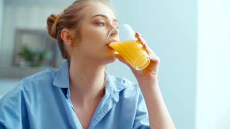 portrait of happy young woman drinking orange juice during breakfast.