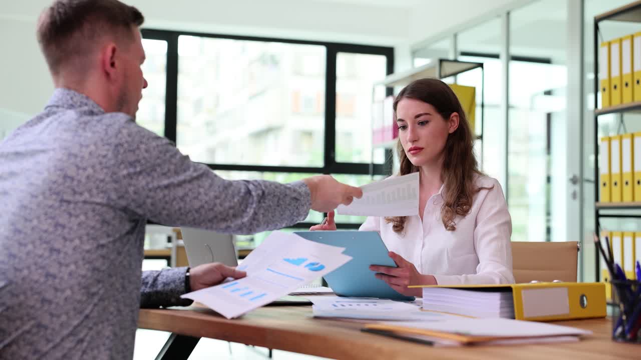 Two colleagues discussing documents in an office