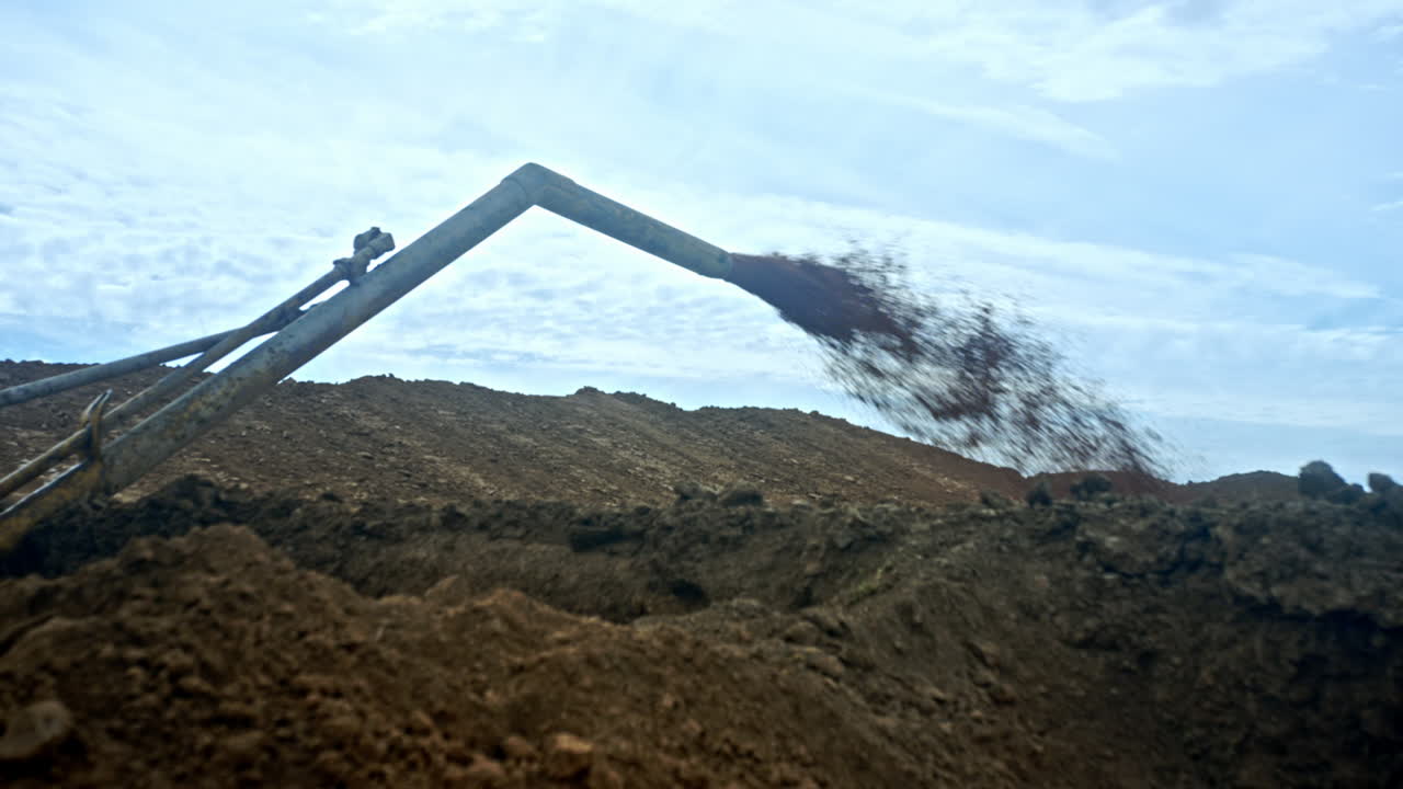 Bent metal pipe produces the dirty flow. Ground piles around. Production of oil and gas.