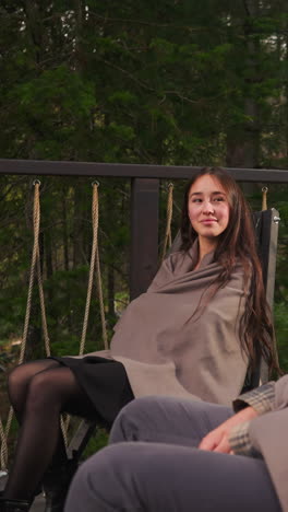 woman looks at man sitting in armchair on terrace. couple immerses in nature embrace during holiday at countryside cottage enjoying romantic honeymoon