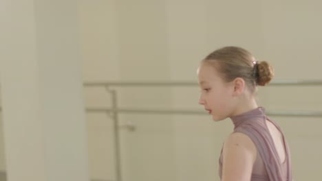 a group of young ballet students in black dancewear practicing positions in a spacious ballet studio with wooden flooring and wall-mounted barres. focused expressions and synchronized movements.