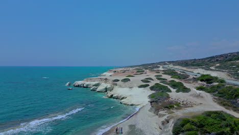 Flying-over-a-couple-swimming-on-a-sandy-bay-amongst-a-rocky-Mediterranean-shoreline