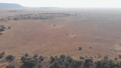 Aerial-shot-seeing-two-mountain-bikers-far-in-the-distance-during-winter