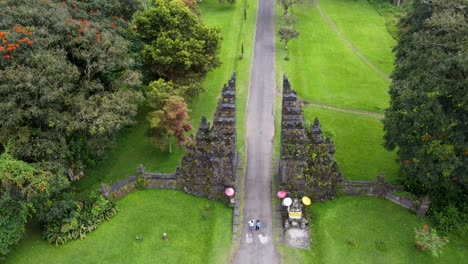 Vista-Aérea-De-Una-Pareja-De-Turistas-Tomando-Fotos-En-La-Famosa-Y-Emblemática-Atracción-Turística-Handara-Gate-En-Bali,-Indonesia