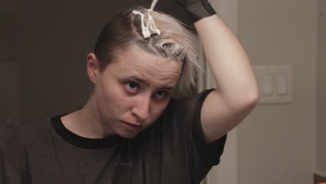 a young lady applying hair bleach cream at home - close up shot