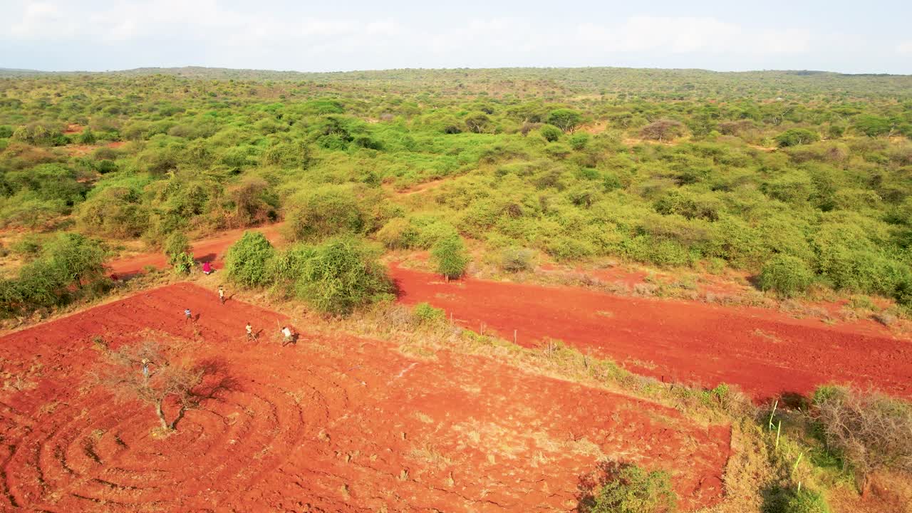 Vista aerea di terreni agricoli rurali con campi di terra rossa e vegetazione arbustiva circostante nel paesaggio semi-arido del Kenya.