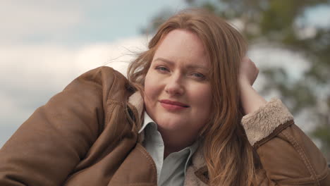 portrait of a sexy red haired woman lying outdoors looking directly at the camera