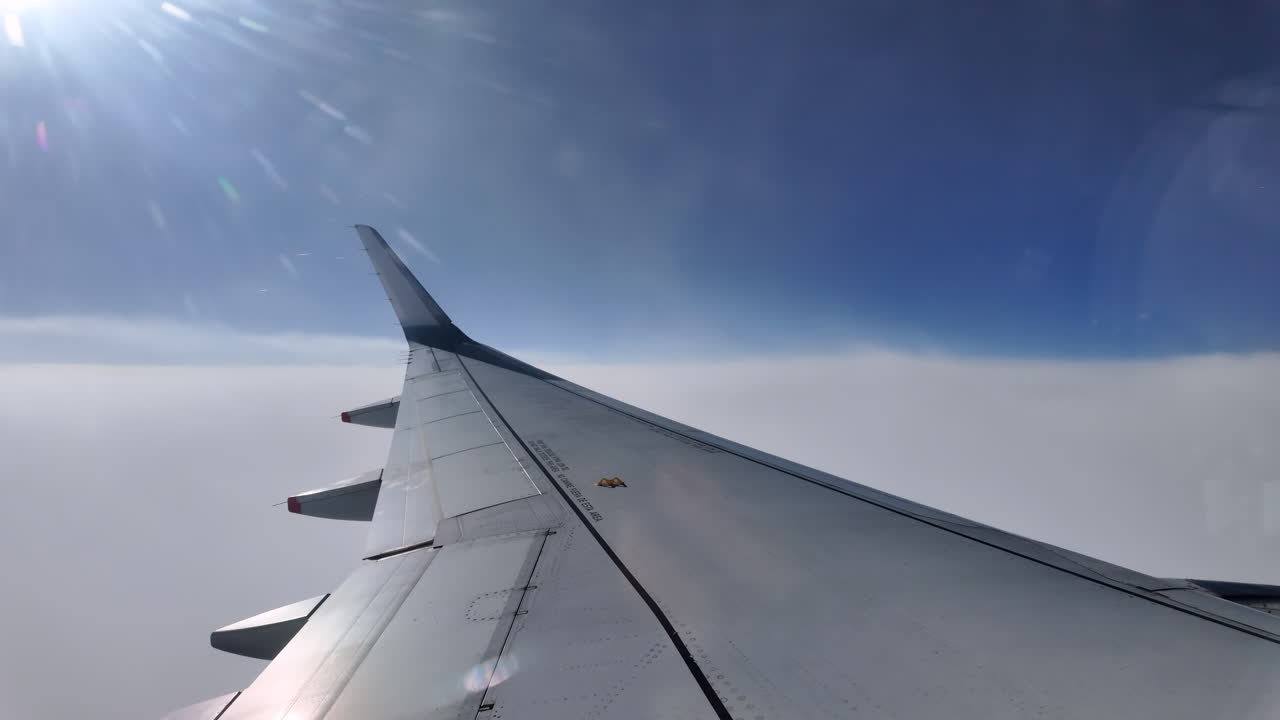 Aircraft wing gliding above layered clouds viewed from the window seat