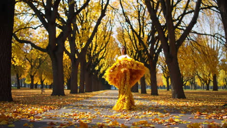 woman in a flowing golden leaf dress in an autumn park