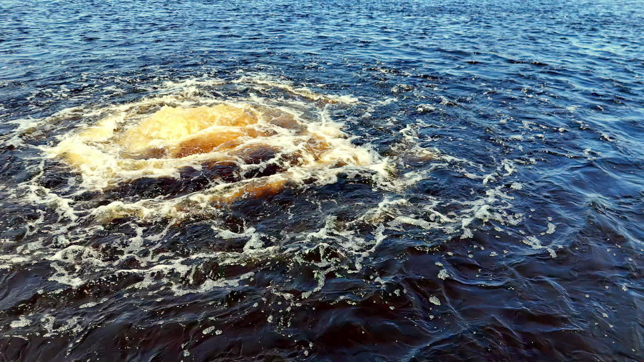 Low-angle view of a turbulent, dark-blue Baltic Sea during Autumn, with a central, massive, yellowish methane gas eruption plume